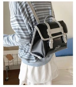Detail of a shiny black and silver backpack with Almajer lettering worn by a model