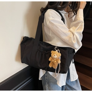 Black nylon shoulder bag with multi-pockets and a cute bear plush pendant in a macro view