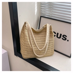 Detail of beige woven straw tote bag with thick padded faux leather handles