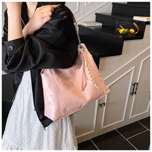 Detail of pink large-capacity tote bag featuring embossed logo and decorative chain strap