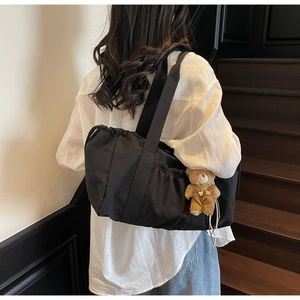 Detail of black nylon drawstring tote bag with soft bear logo and cute plush charm