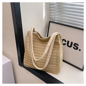 Detail shot of the beige straw tote bag showing the fine woven texture and shoulder strap