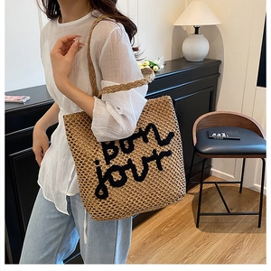 Détail du sac cabas en paille tissée avec lettrage bonjour brodé noir et texture