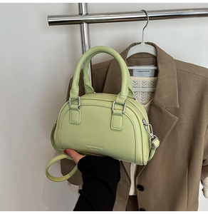Détail du sac bowling en cuir grainé vert clair avec texte embossé et poignée chic
