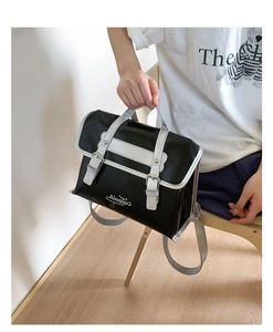 Close-up of black glossy leather satchel featuring silver buckles and retro double straps