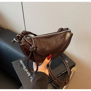 Dettaglio borsa croissant marrone scuro in pelle lucida a pieghe con tracolla annodata