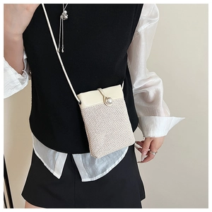 Detail of woven straw mobile phone bag with cream leather flap and pearl buckle