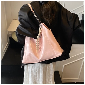 Detail of pink patent leather tote bag with metal chain strap and brand embossing