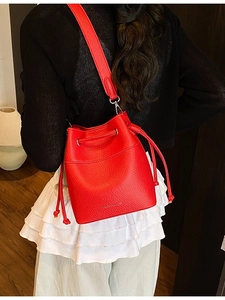 Chic red lychee leather bucket bag with drawstring closure and wide shoulder strap