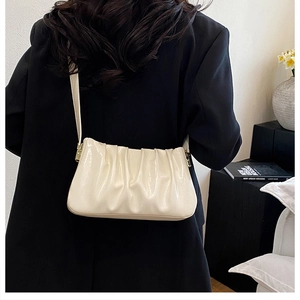 Detail of a creamy pleated cloud bag on a model shoulder with elegant gathered leather texture