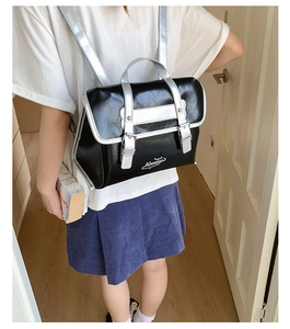 Side view of a student-style black and silver backpack worn on back in home hallway