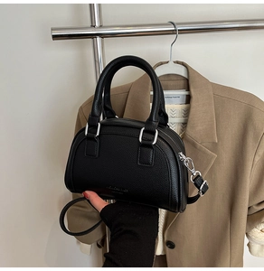 Détail d'un sac bowling noir en cuir grainé avec finitions argentées et deux anses