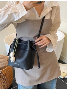 Minimalist black lychee leather bucket bag with drawstring and white tulip pendant charm