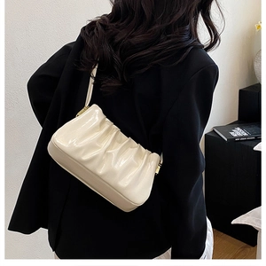 Close-up of cream white pleated shoulder bag in glossy patent leather finish