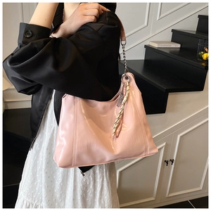Pink glossy faux leather tote bag detail with embossed lettering and metallic chain strap