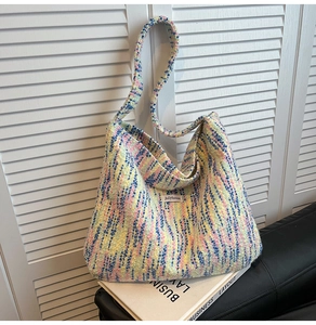 Detail der bunten Strickstruktur und des gewebten Schultergurts dieser Tragetasche