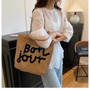 Détail de la broderie Bonjour sur un sac cabas en paille tissée avec motif ajouré chic