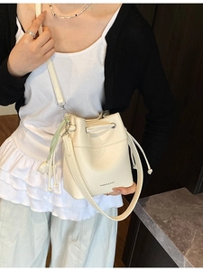 White lychee pattern bucket bag with tulip charm shown cross-body on a model