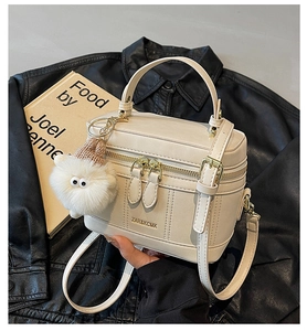 Détail du sac seau blanc crème avec fermetures dorées et breloque en peluche douce