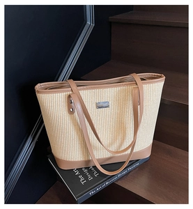 Detailed macro view of woven straw tote bag with brown leather trim and metal zipper close