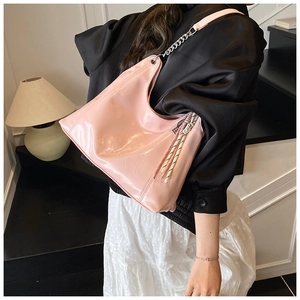 Detail of pink faux leather hobo bag with silver chain and woven rope charm