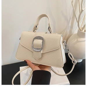 Detail der cremeweißen Mini-Tasche aus Narbenleder mit gravierter silberner Schnalle