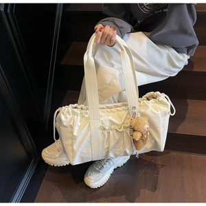 Detail of off-white drawstring canvas tote bag with cute plush bear pendant accessory