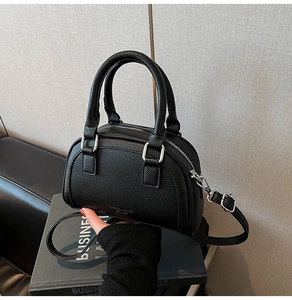 Vue détaillée du sac bowling noir à grain litchi avec poignées et détails argentés