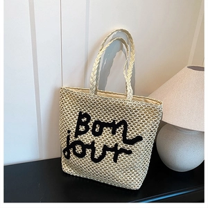 Détails du tressage en paille et broderie Bonjour sur un sac cabas d'été beige