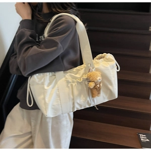 Detail of off-white multi-pocket tote bag with a cute brown teddy bear plush charm