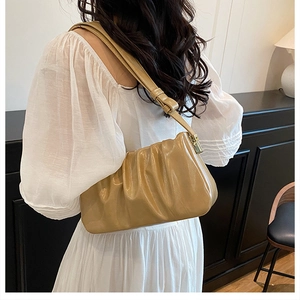 Detail view of khaki pleated cloud bag featuring PU leather texture and gold metal clasp