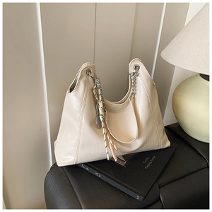 Detail of cream glossy tote with HUAN YOU embossed logo and silver chain strap accent
