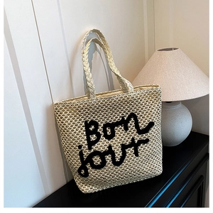 Détail du sac cabas beige en paille avec broderie Bonjour noire et poignées tressées