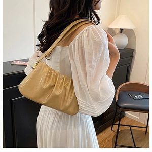 Detail shot of apricot pleated cloud bag showing fine leather texture and soft strap