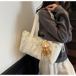 Detail view of canvas tote bag featuring ruffled edges and a cute plush bear pendant