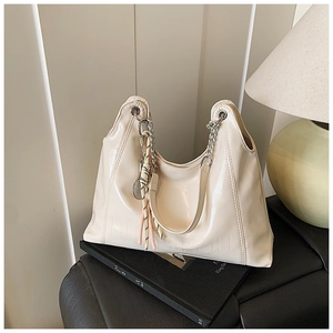 Detail of cream hobo tote with glossy finish, silver chain strap and tennis charm
