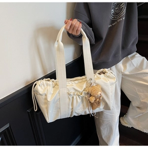 Detail of cream canvas tote bag with drawstring closure and cute bear charm pendant