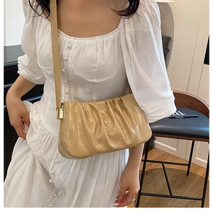 Detailed close-up of a beige ruched cloud bag with soft leather texture and gold hardware