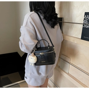 Détail d'un sac à main noir structuré avec un porte-clé mouton en peluche blanche