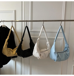 Detail of pleated dumpling bags in yellow, black, white, and blue with knot handle