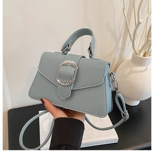 Detail einer hellblauen Handtasche aus Kieselleder mit strukturierter Metallschnalle