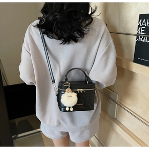 Vue arrière du mannequin portant un sac seau noir avec un pendentif d'agneau blanc