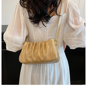 Detail of beige pleated cloud bag showing soft texture and premium metal zipper finish