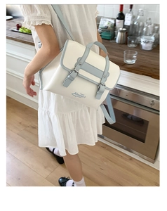 Detail of artistic white and blue dual-color backpack on a model in a cozy kitchen