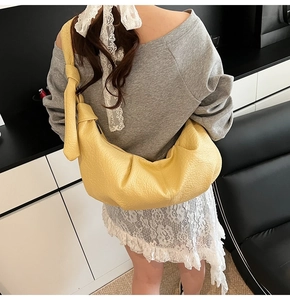 Detailed side view of yellow pleated hobo bag with knotted strap on model's shoulder