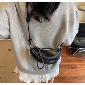 Dettaglio della borsa a mezzaluna in pelle nera con cerniera e tracolla con nodo decor