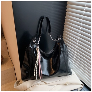Detailed macro view of black patent leather tote bag with embossed brand logo on bottom