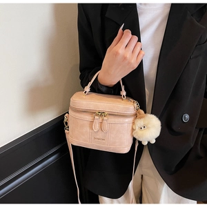 Détail du sac de toilette en cuir rose avec garniture dorée et breloque mouton en peluche