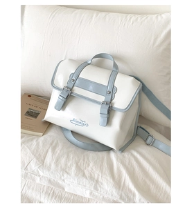 Close-up of white and light blue satchel bag on a soft pillow with a book background
