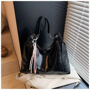 Detail of glossy black tote bag with silver chain strap and colorful woven charms
